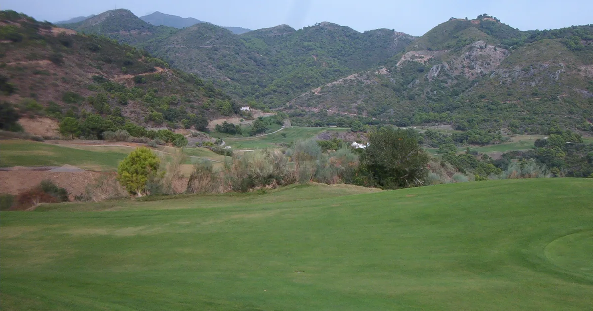 Green golf fairway below wooded hills in Benahavís, inland from Marbella