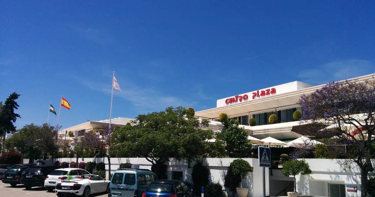 Centro Plaza shopping centre in Nueva Andalucía, Marbella, with trees and parked cars in front