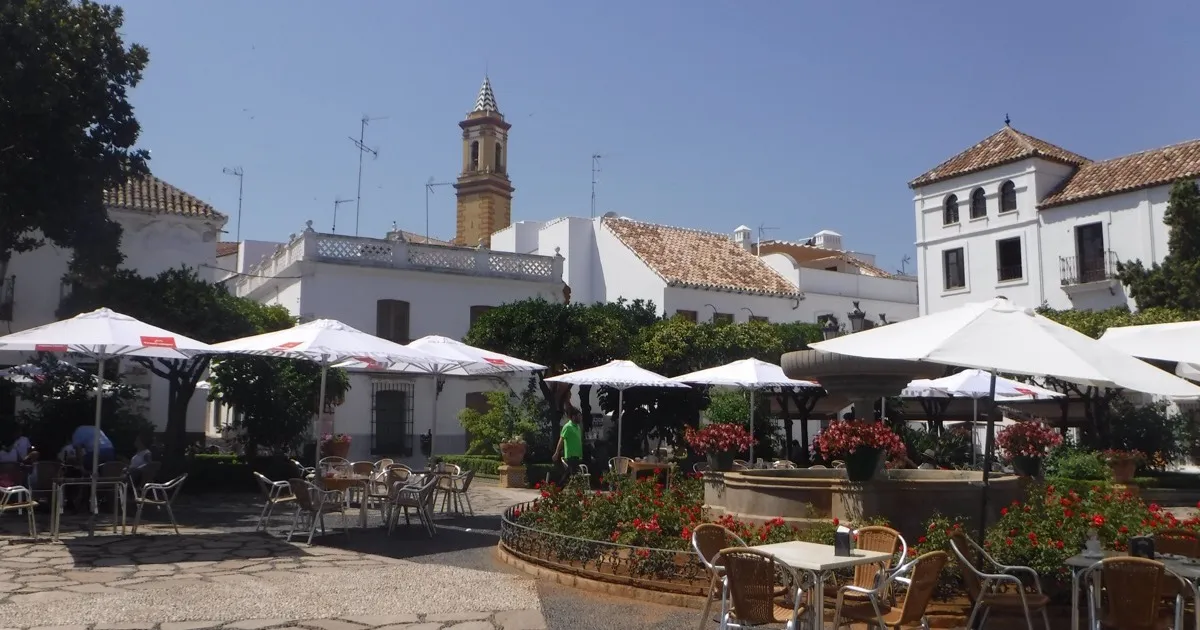 Plaza de las Flores in Estepona old town — whitewashed Andalusian square with flowers and cafe terraces, Estepona vs Marbella escort weekend 2026