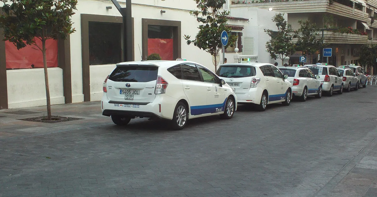 White Marbella taxis with the town's blue stripe waiting at a rank — getting around without a car
