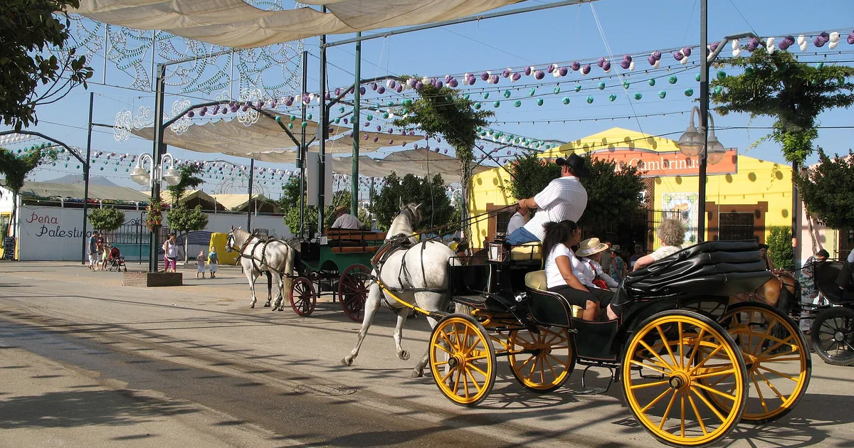 Horse-drawn carriage under the paper lanterns of the Málaga Feria — day-trip guide from Marbella
