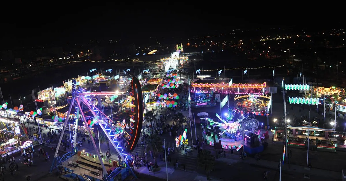 Night view over the lit-up feria ground of San Pedro Alcántara, Marbella, with fairground rides and casetas